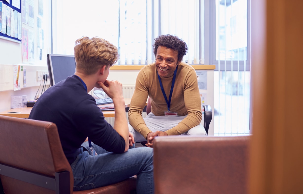 Two men engaged in conversation while seated in a waiting room.