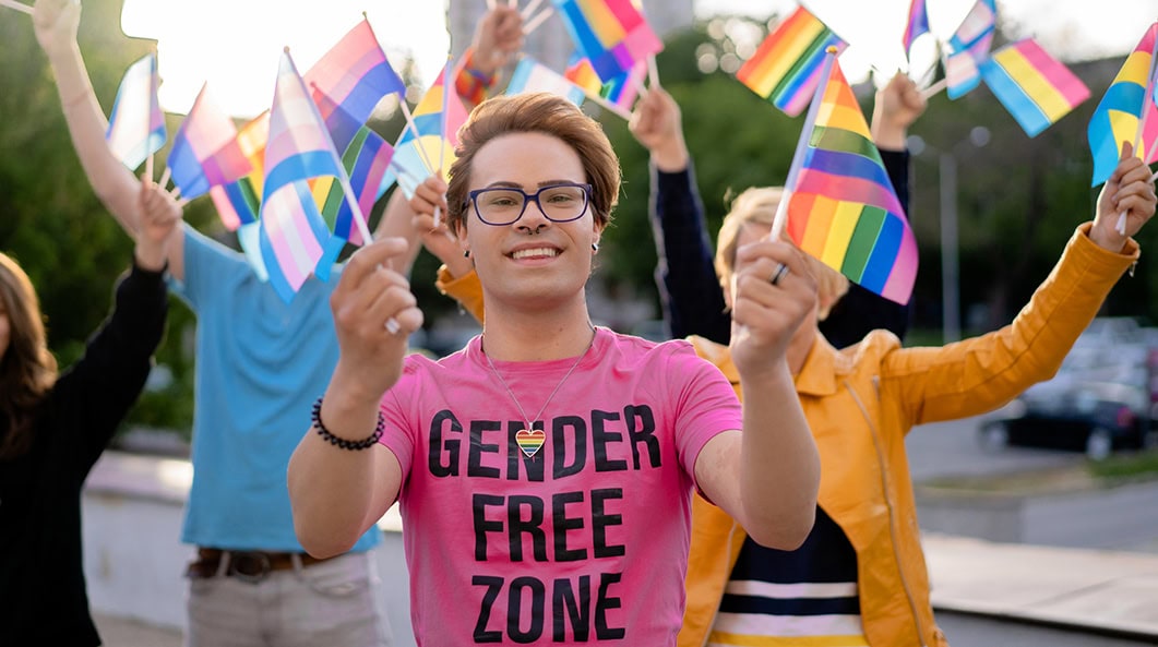 Transgender young person is shown holding Pride flag